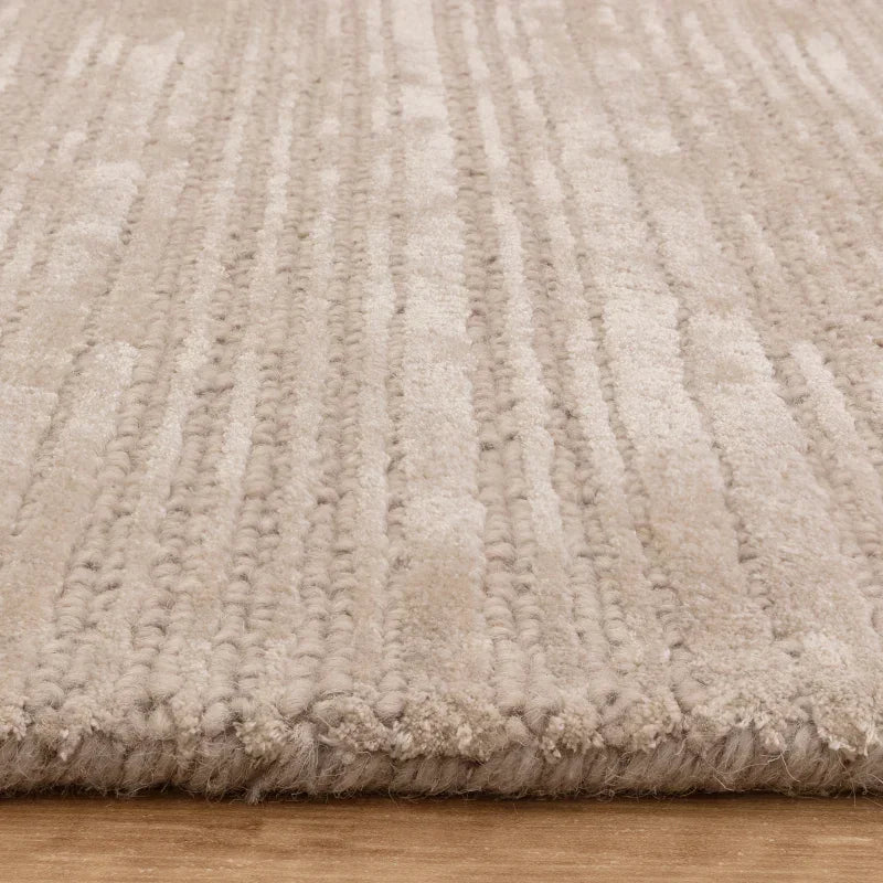 Beige textured rug with raised striped pattern on wooden floor, close-up angle