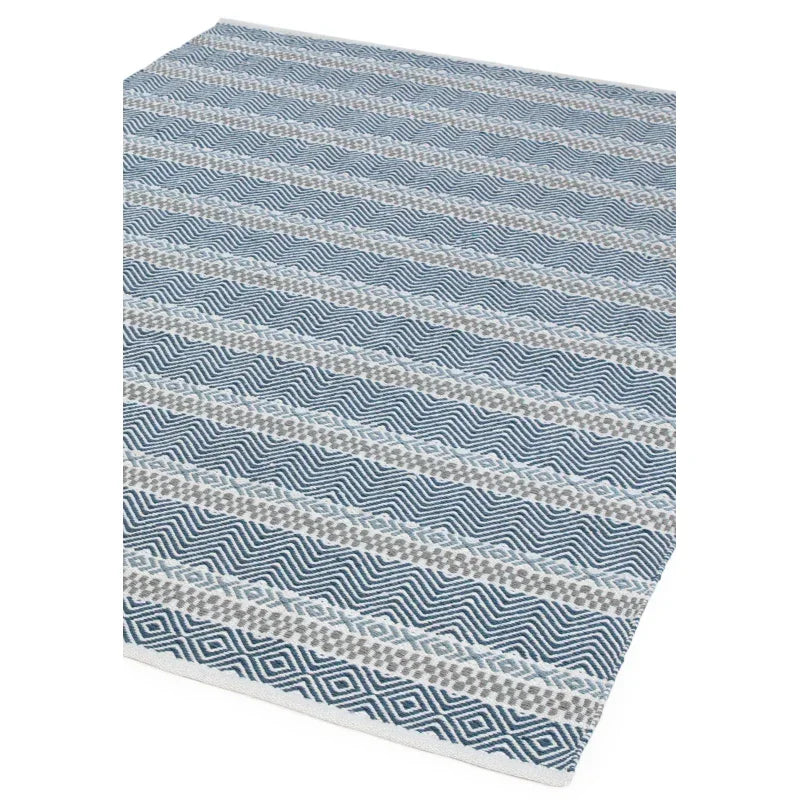 Blue geometric patterned rug with diamond and zigzag detailing on white background