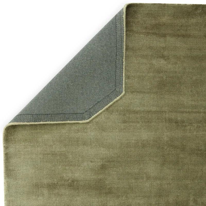 Green velvet area rug with corner flipped to show backing detail