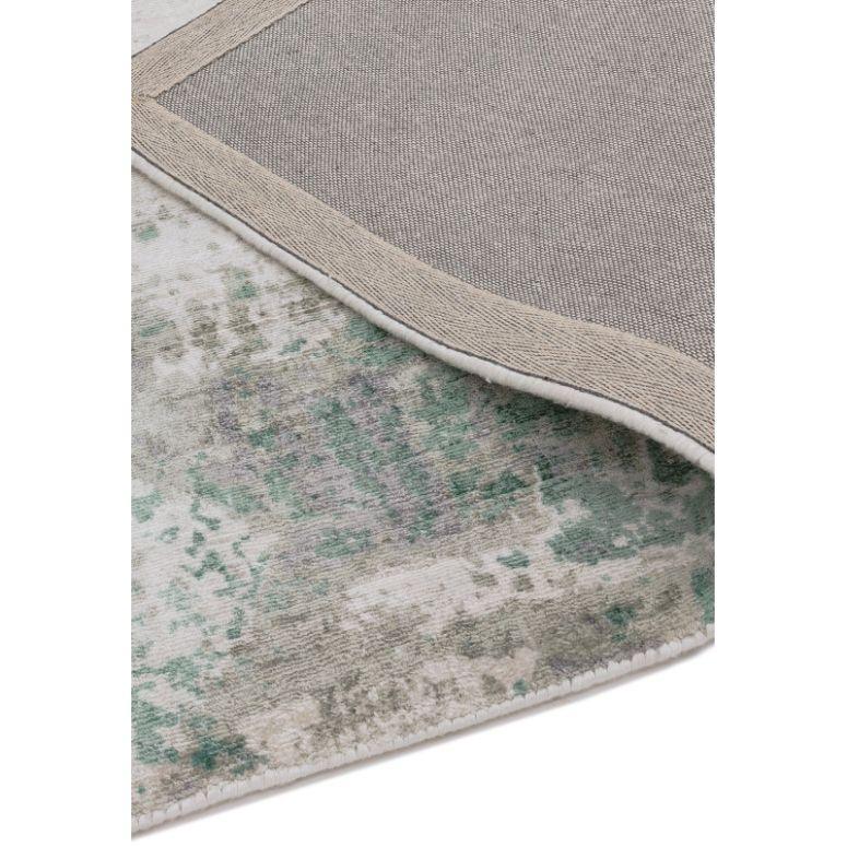 Green and grey patterned rug with corner flipped to show textured backing