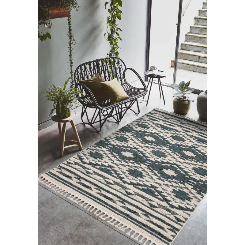 Geometric patterned area rug with fringed edge in modern living room with black rattan sofa