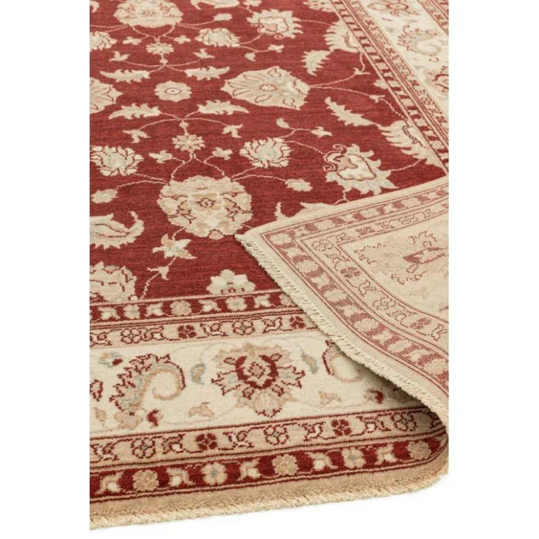 Red and cream traditional patterned rug with floral motifs and fringed edge corner view