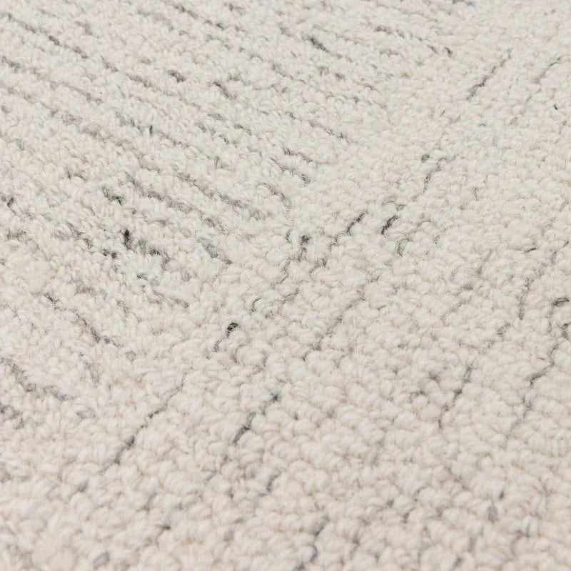 Close view of cream textured rug with subtle grey lines and loop pile details