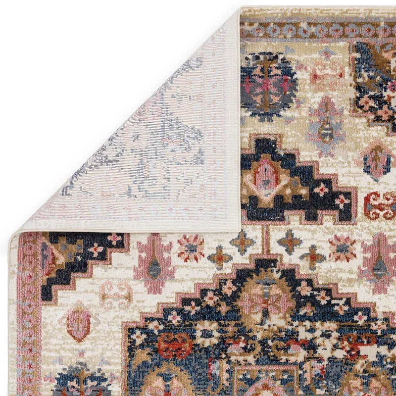 Traditional patterned area rug with ornate navy, beige, and pink detailing, corner flipped