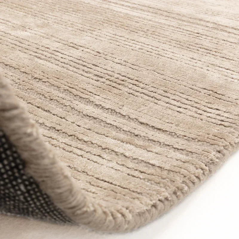 Beige textured area rug with subtle linear pattern and rolled edge detail