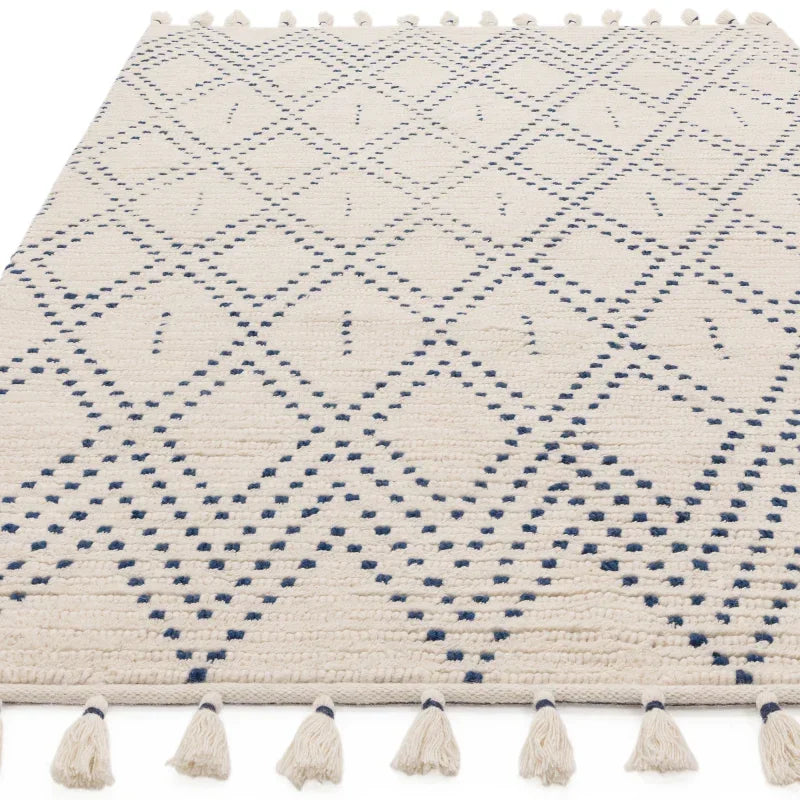 Cream geometric rug with blue diamond pattern and tassel edging, flat lay view
