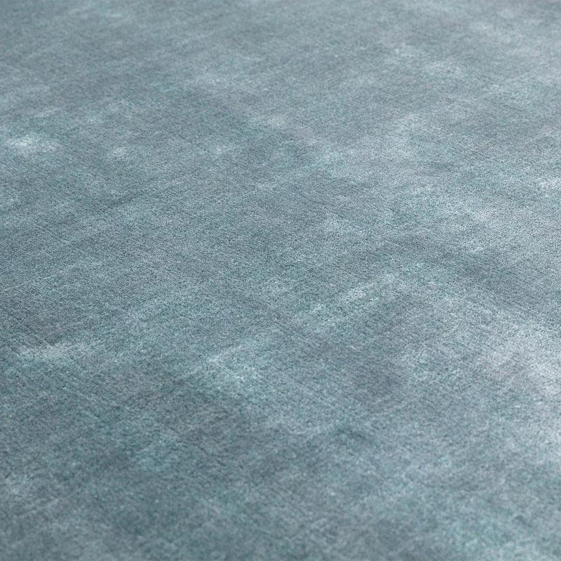 Closeup of blue textured rug fabric surface, showing subtle pattern and soft finish