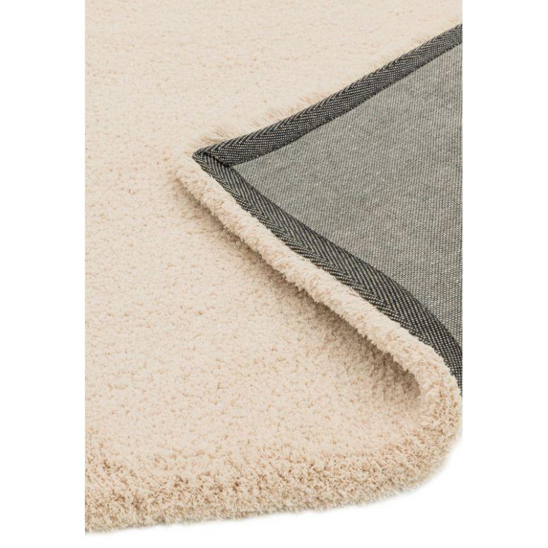 Cream shaggy rug with textured pile and corner showing grey backing