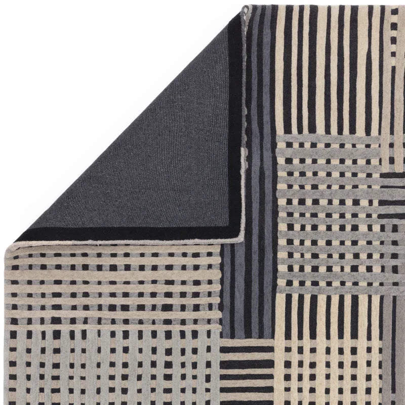 Geometric patterned rug in black, grey and beige with corner folded to show reverse side