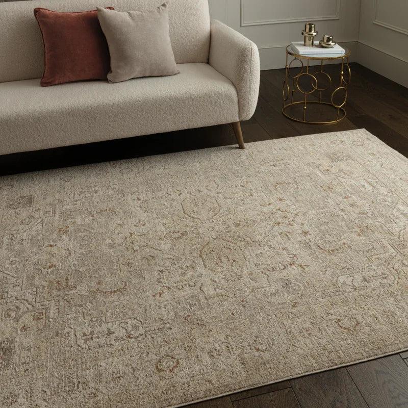 Beige patterned area rug on dark wooden floor beside cream sofa and round side table
