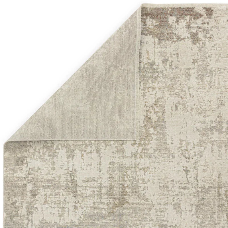 Beige and grey area rug with abstract pattern and turned-up corner