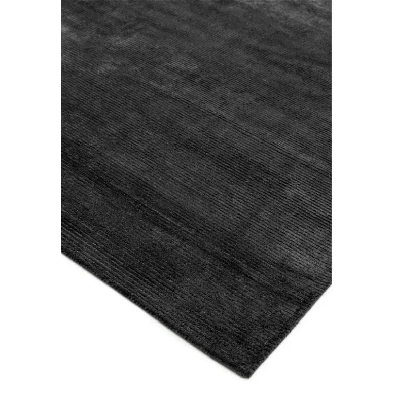 Charcoal grey area rug with subtle textured pattern, close corner view on white background