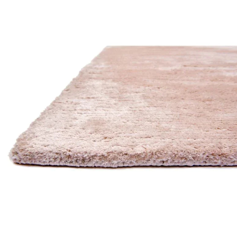 Beige shaggy rug corner with thick pile closeup on white background