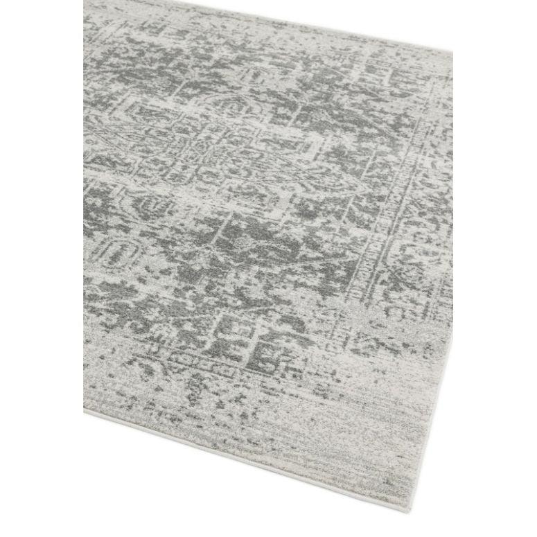 Grey patterned area rug with faded design on light background, corner angle view