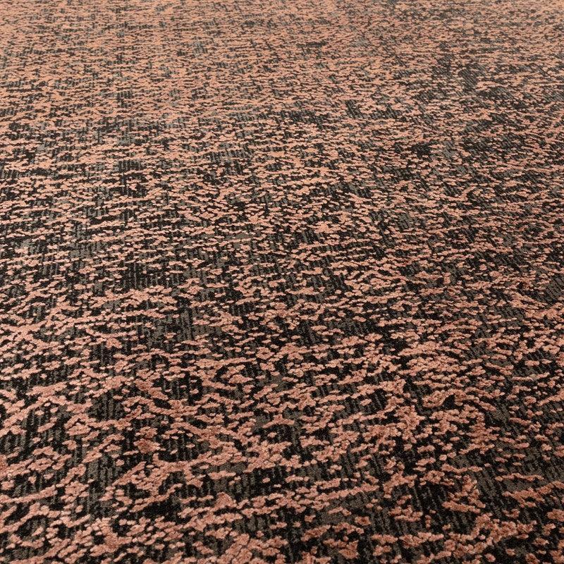 Textured area rug with rose and dark grey abstract pattern, close-up view of carpet surface