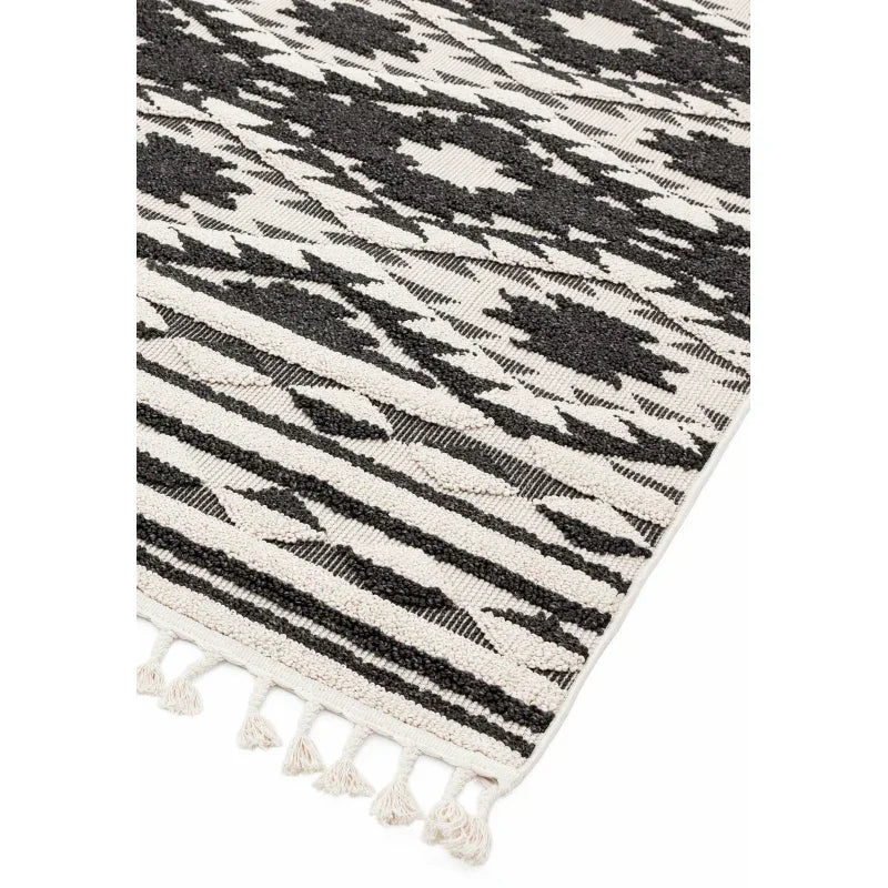 Black and cream patterned rug with tasselled edge and textured woven detail