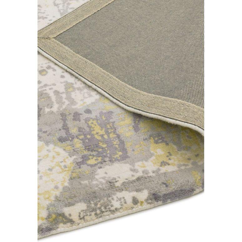 Abstract patterned area rug in grey, yellow and cream colors with a folded corner view