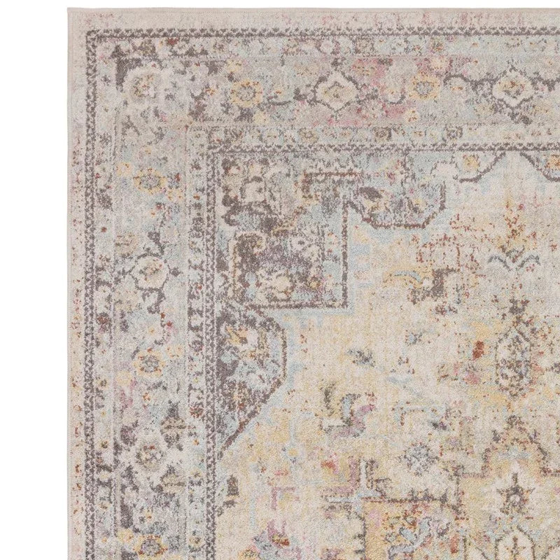 Distressed beige and grey patterned rug corner with ornate border design