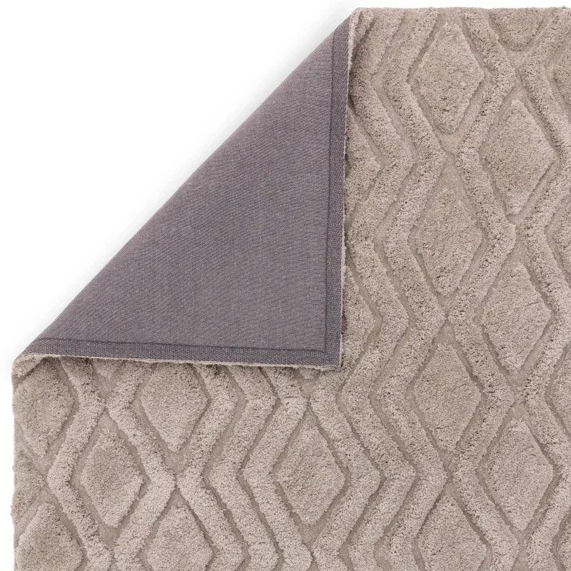 Beige geometric patterned rug corner folded showing textured surface and backing