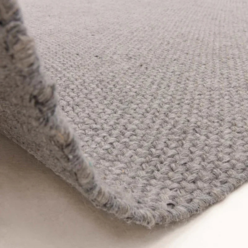 Grey woven rug closeup showing textured wool surface and edge detail