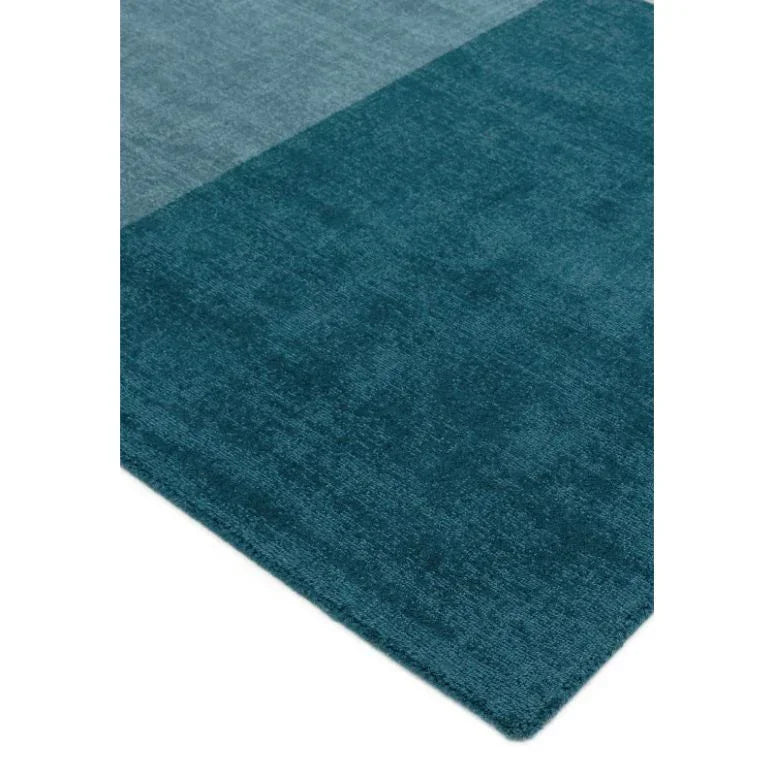 Closeup of two-tone teal area rug with visible soft texture and straight edge