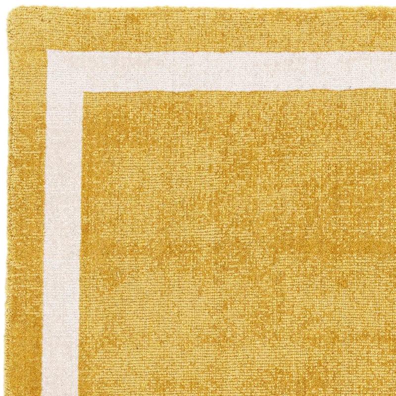 Mustard yellow rug with white border detail, close-up of textured corner