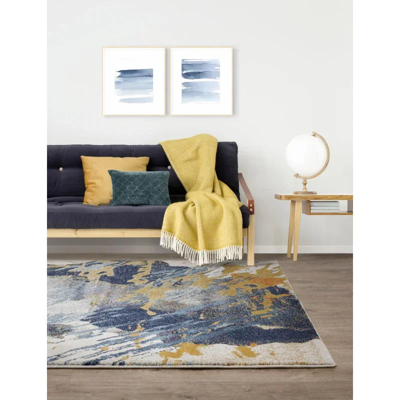 Modern living room with abstract blue and gold area rug, navy sofa, and yellow throw blanket