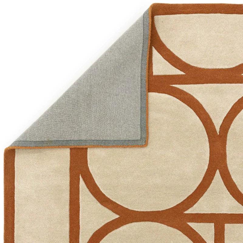 Beige and terracotta geometric rug with visible corner and grey fabric backing