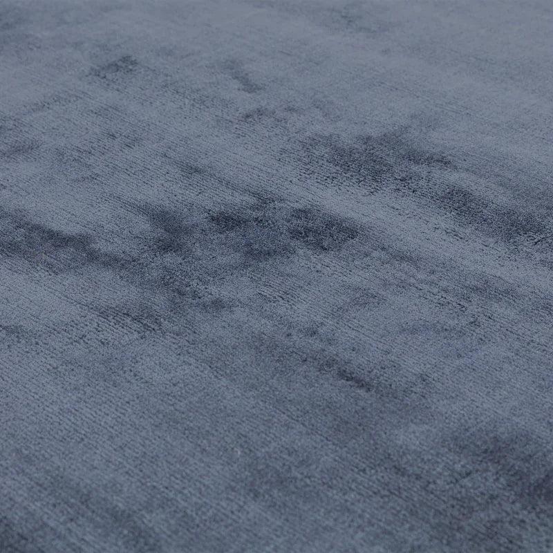 Closeup of a grey velvet rug surface showing soft texture and subtle sheen
