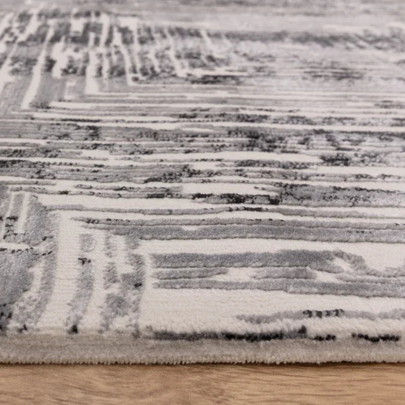 Close-up of grey and white abstract patterned area rug on wooden floor