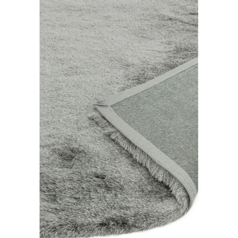 Close up of grey faux fur rug with visible soft pile and turned corner showing backing