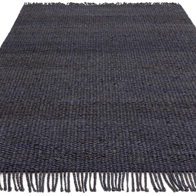 Dark blue woven rug with textured pattern and fringe edging, shown from a low angle