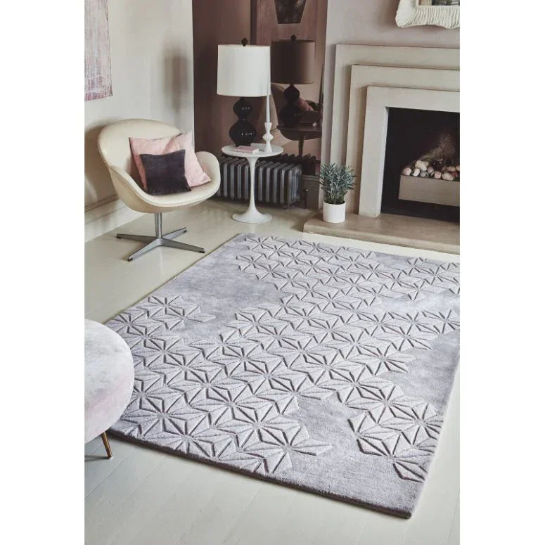 Light grey geometric patterned rug in modern living room with chair and fireplace