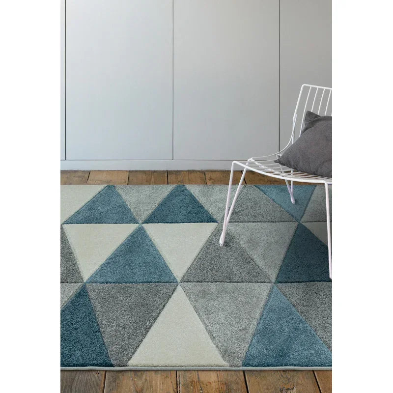 Geometric patterned rug in blue, grey and cream beside white metal chair with cushion