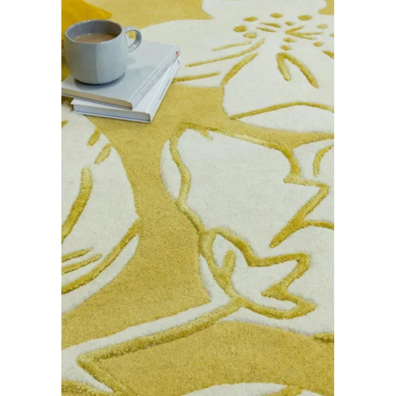 Yellow and cream floral rug with textured pattern and cup on stacked books