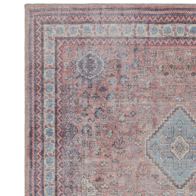 Traditional patterned area rug with muted red, blue, and beige tones, close-up corner view