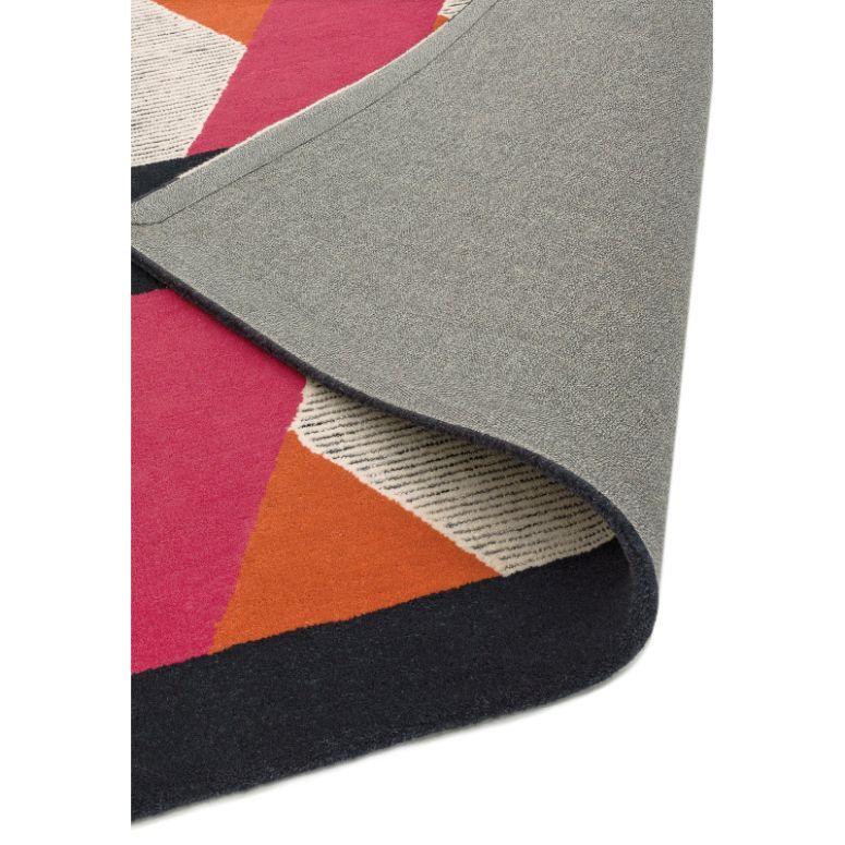 Geometric wool rug with pink, orange and cream shapes, corner folded to show backing