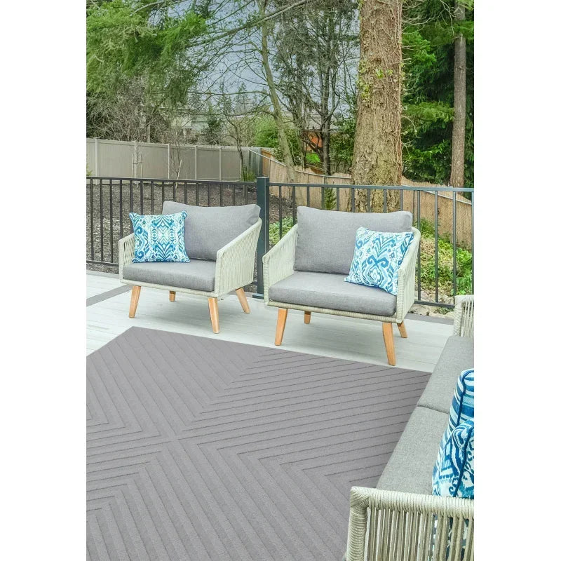 Grey outdoor armchairs with rope detailing and patterned blue cushions on patio