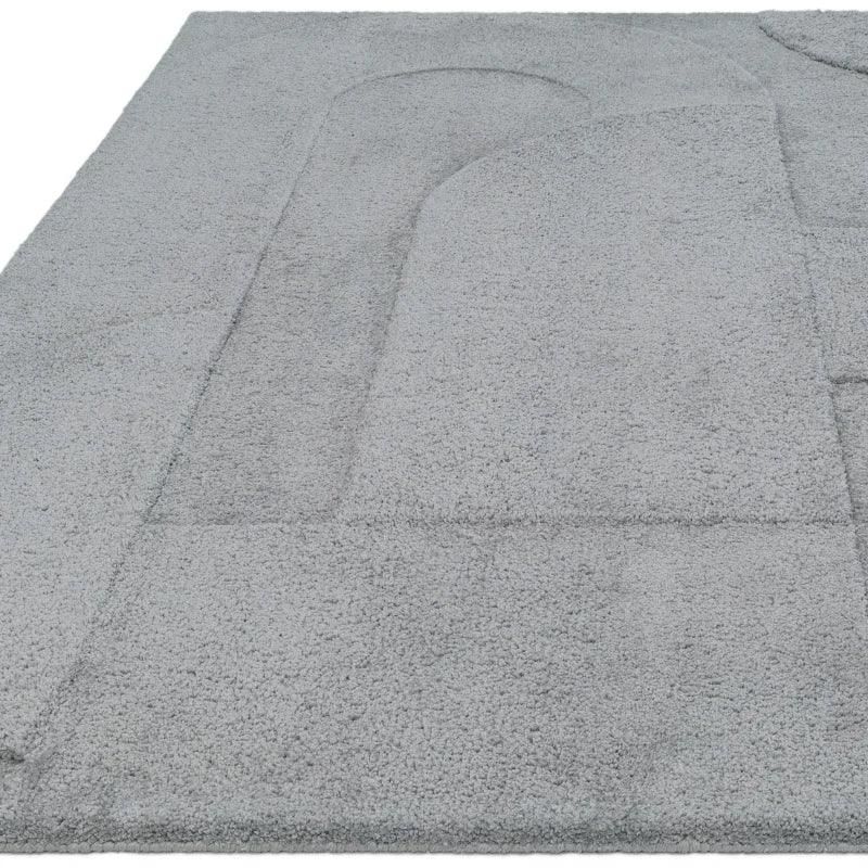 Light grey textured rug with raised abstract arch pattern, close-up corner view