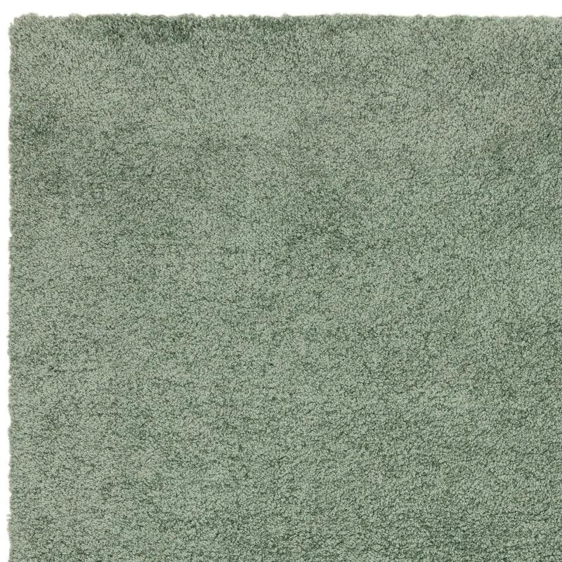 Green shaggy rug close-up showing soft pile texture and rectangular corner