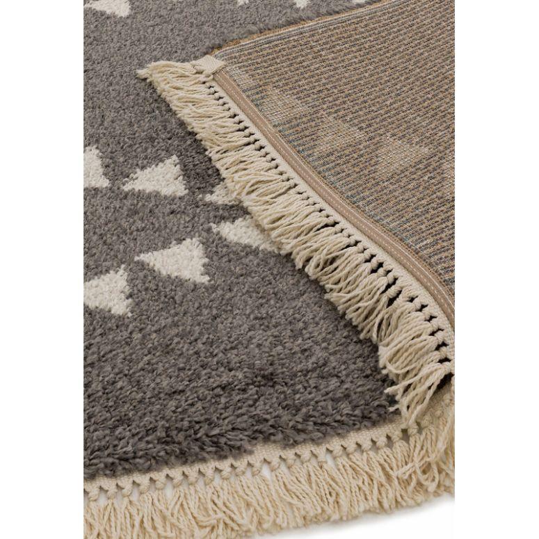 Grey patterned rug with cream triangle design and fringe detail, corner flipped over