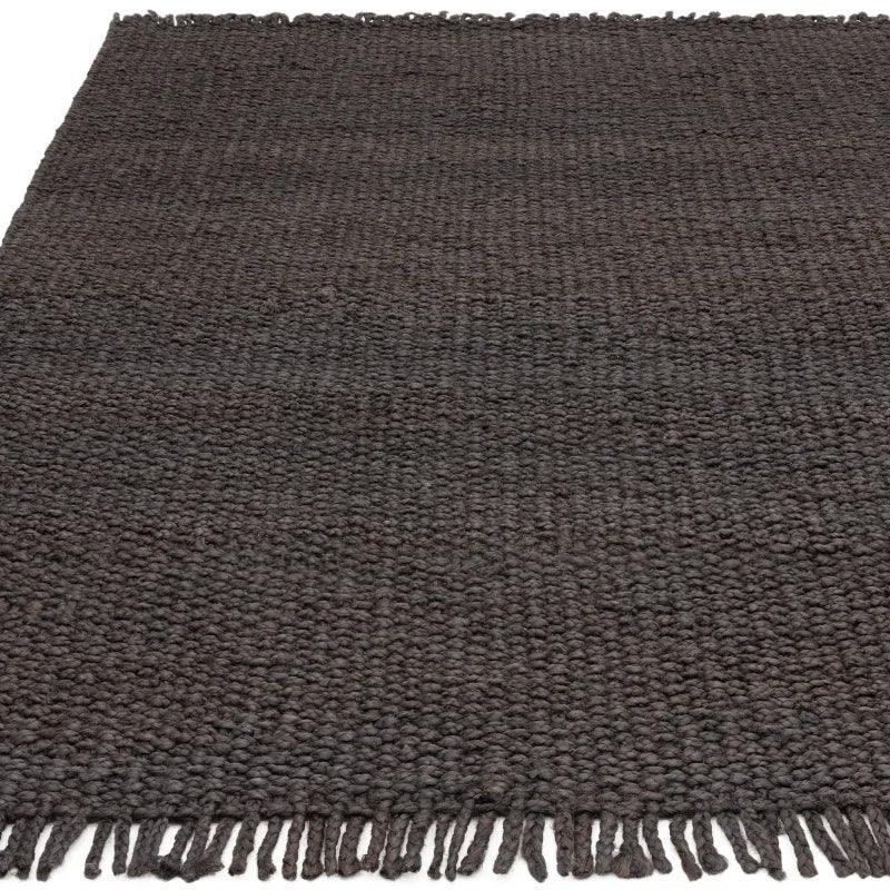 Charcoal woven rug with textured surface and tassel fringe detail