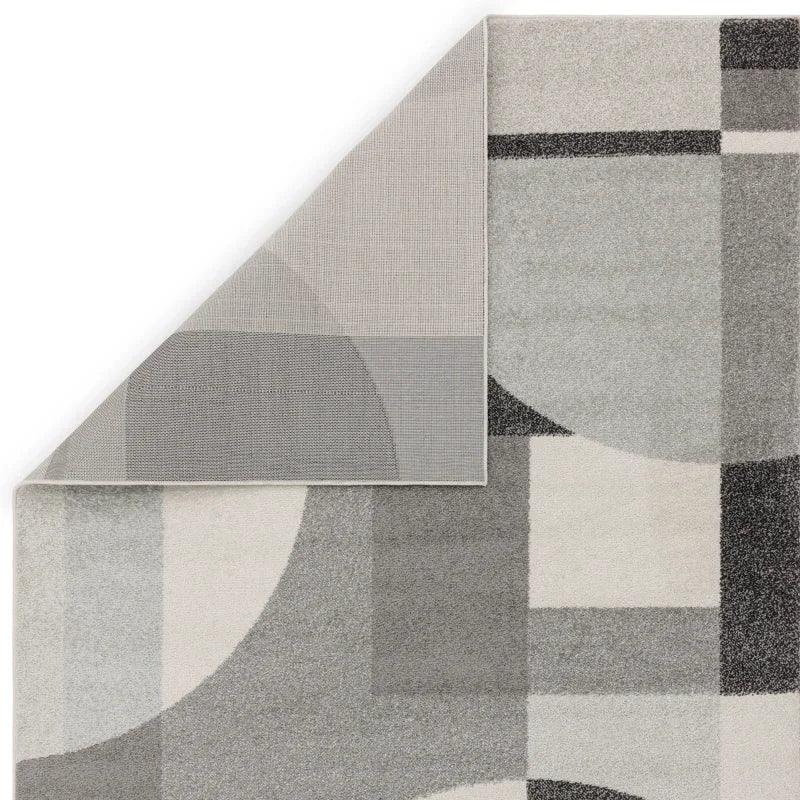 Grey geometric area rug with corner folded to show non-slip backing