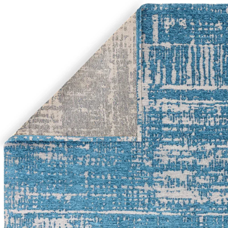 Blue and grey abstract patterned area rug corner detail with exposed backing