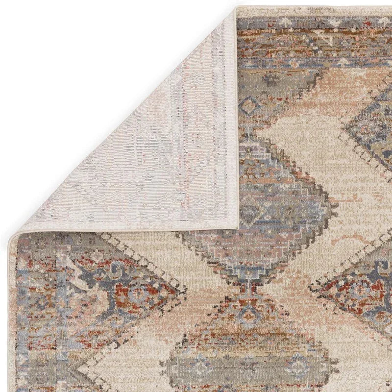 Beige and blue patterned area rug with corner flipped to show backing detail