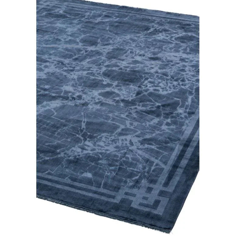 Navy blue area rug with marble effect pattern and geometric border on corner view
