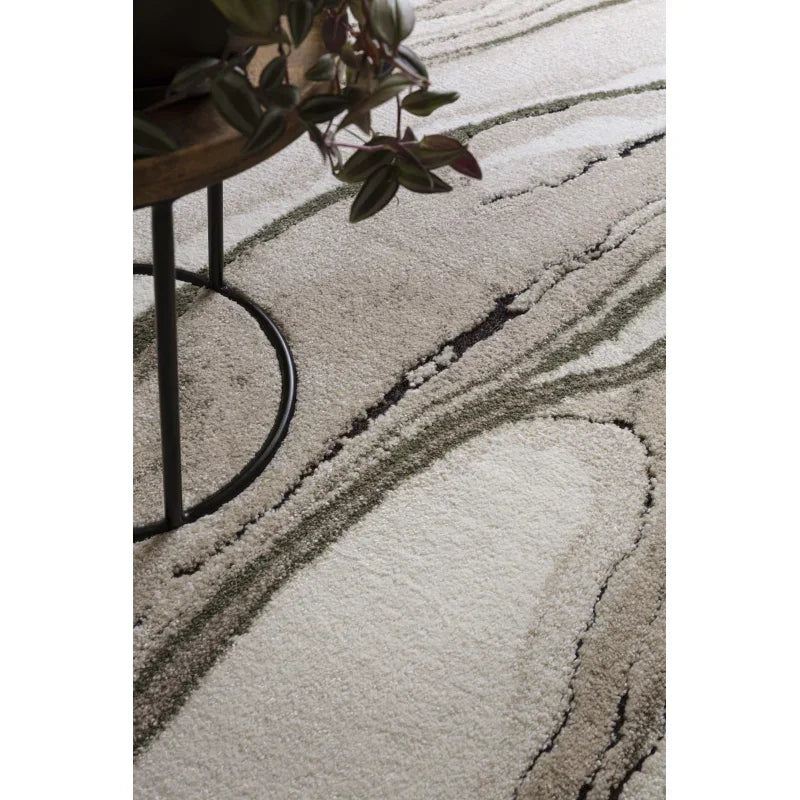 Modern abstract area rug with green and beige swirls beside a metal-legged table