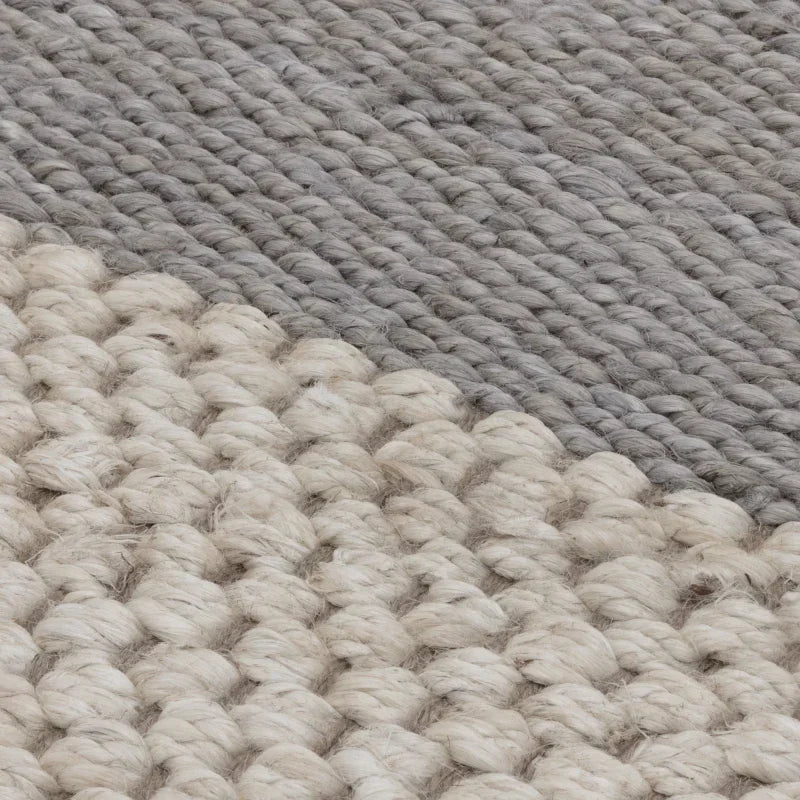 Closeup of chunky wool rug in cream and grey tones showing textured weave