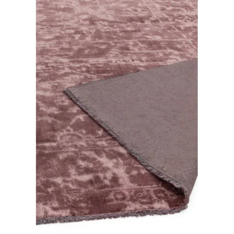 Plum velvet area rug with textured pattern, corner flipped showing backing