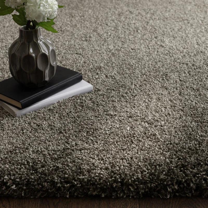 Grey shaggy rug on wooden floor with vase and books for living room decor